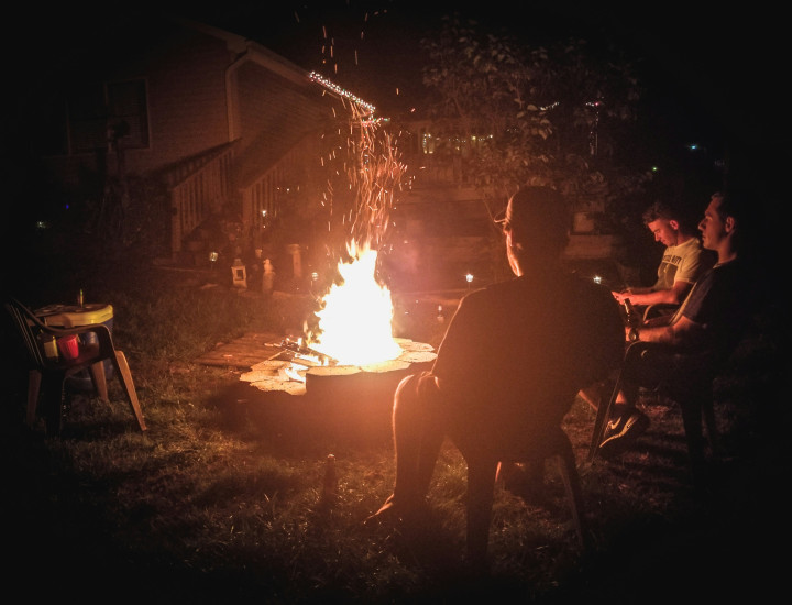 Picture of camp fire. People sitting in front of it.